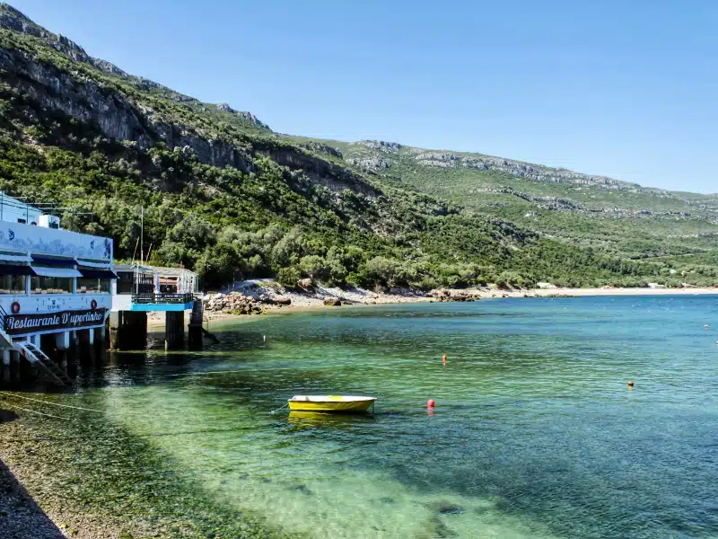 Crystalline waters of Portinho Beach between mountains in Portugal