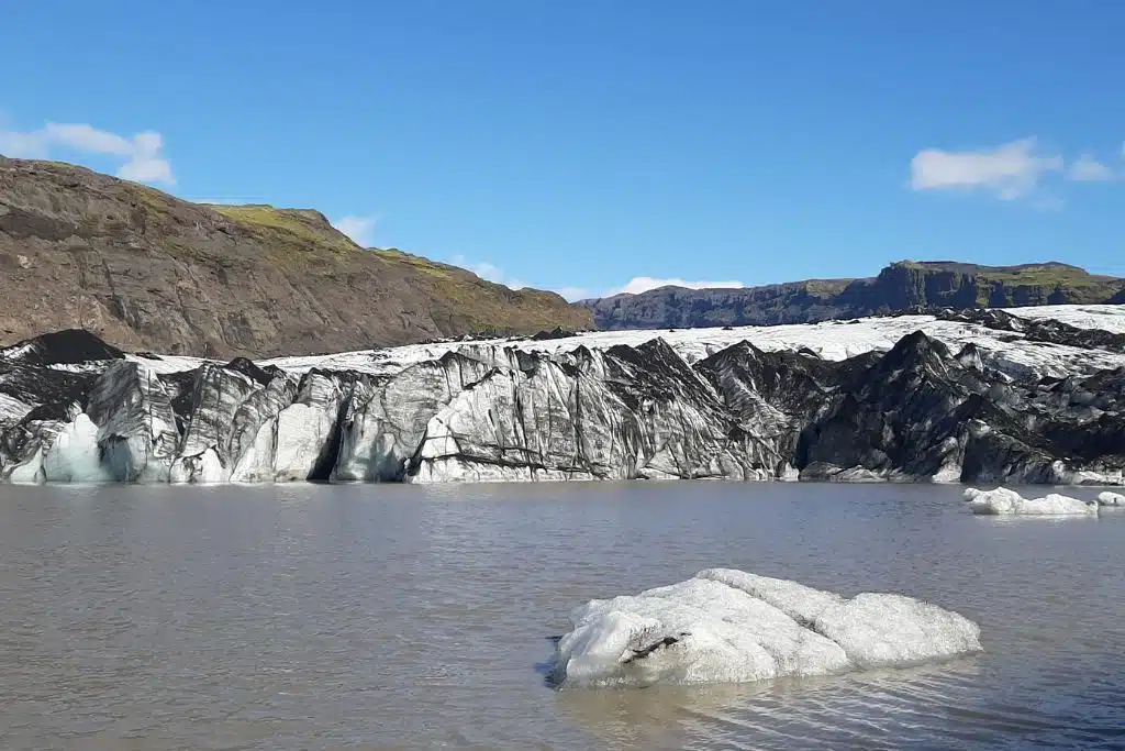 large glacier stretching between rocky hills to water