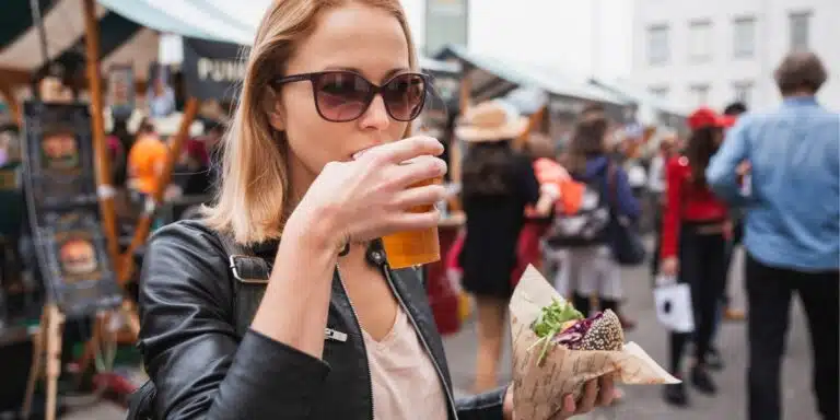 woman eating and drinking at a street food festival