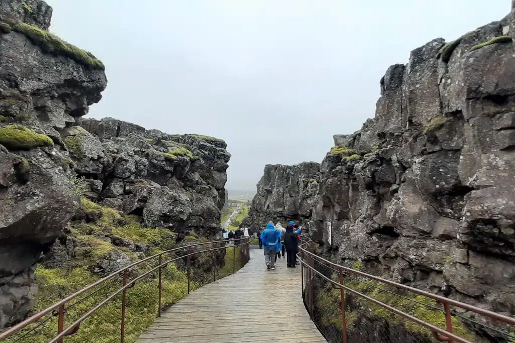 Walking along a boardwalk between rocky tectonic plates in Iceland