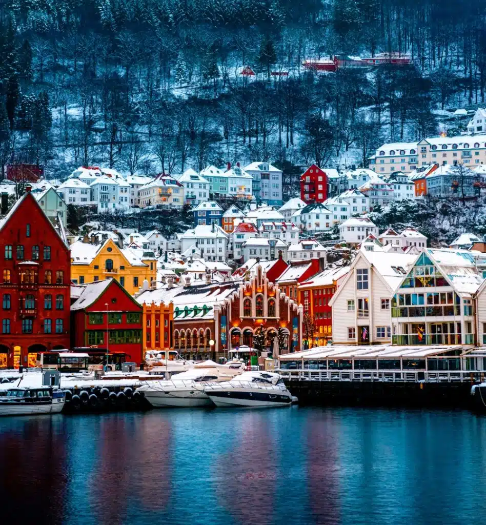 Bergen city with famous Bryggen merchandise wooden houses and lights in snow season at evening. 