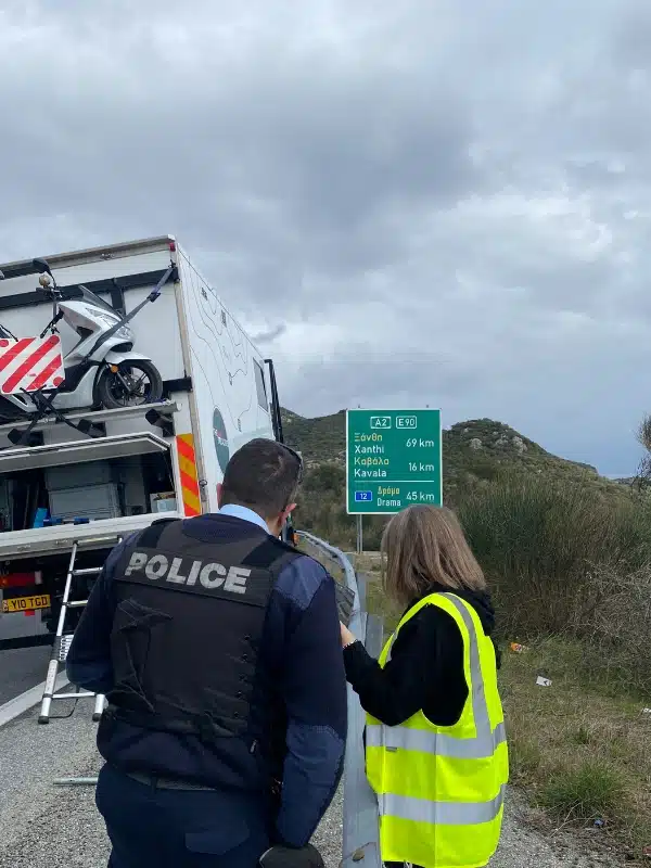 woman in a hi-vis jacket talking to a policeman by the side of a motorway