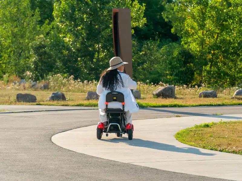 ing a straw hat on a lightweight mobility scooter in a park