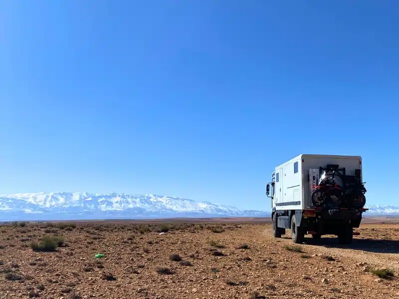 overland truck on a stony desert track with views of distant snow capped mountains