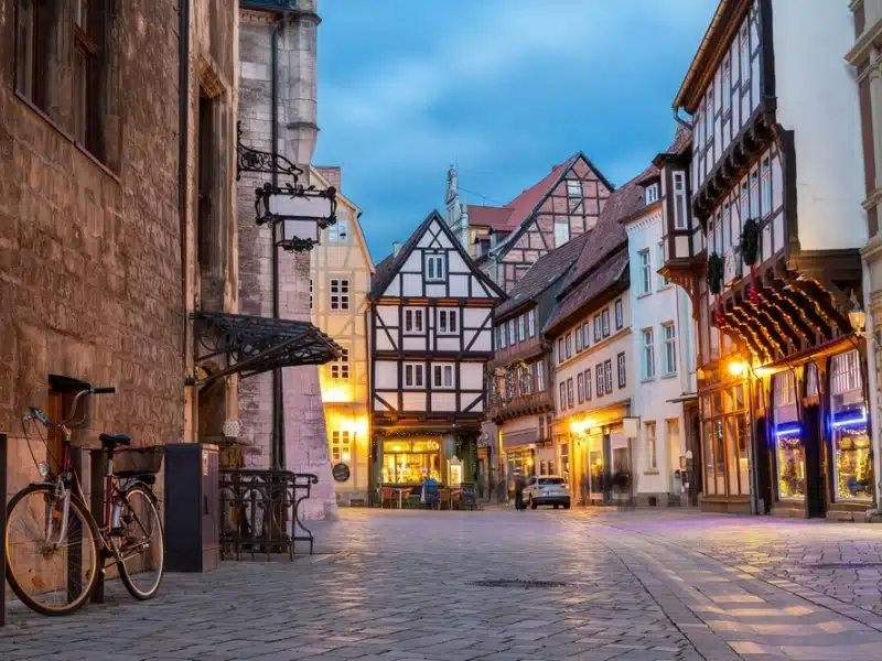 Charming Quedlinburg town evening street view illuminated with lights old St. Nicholas Church St. Nicholas Kirche cafe restaurant  historical half-timbered houses facade. Festive city German