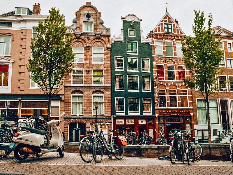 Traditional Dutch houses lining a canalside street with bikes and a moped