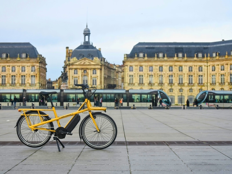 Electric bike and tram in front of historic buildings in Bordeaux