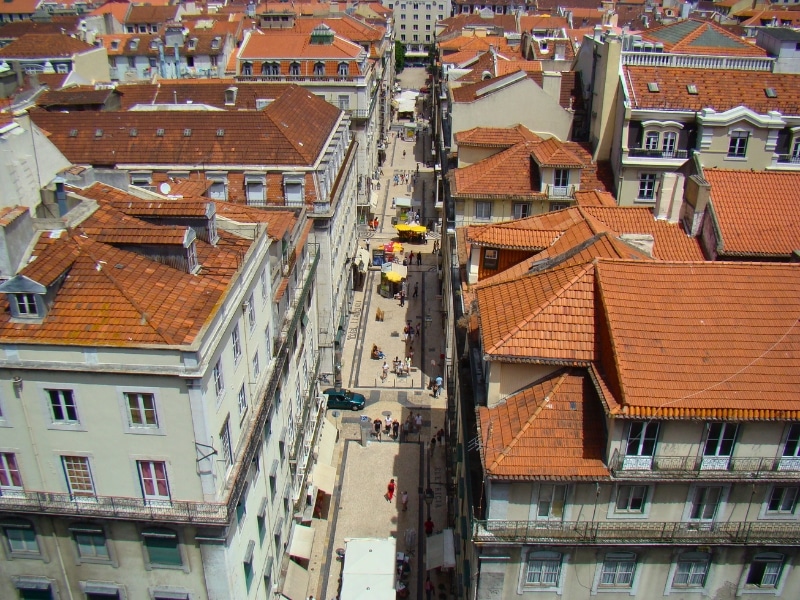 Terracotta tiled roofed buildings on a city street with food stalls and cafes in the wide street