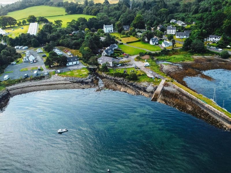 aerial view of a Scottish harbour backed by a small village of white painted houses