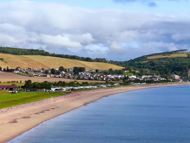 Shot of a beach and fields with a small campsite behind the beach