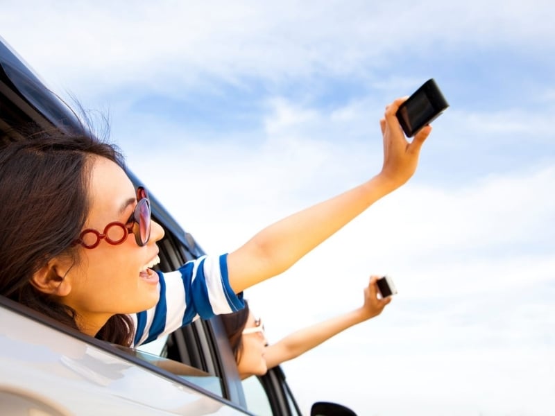Teenagers listening to music and taking photos on a road trip