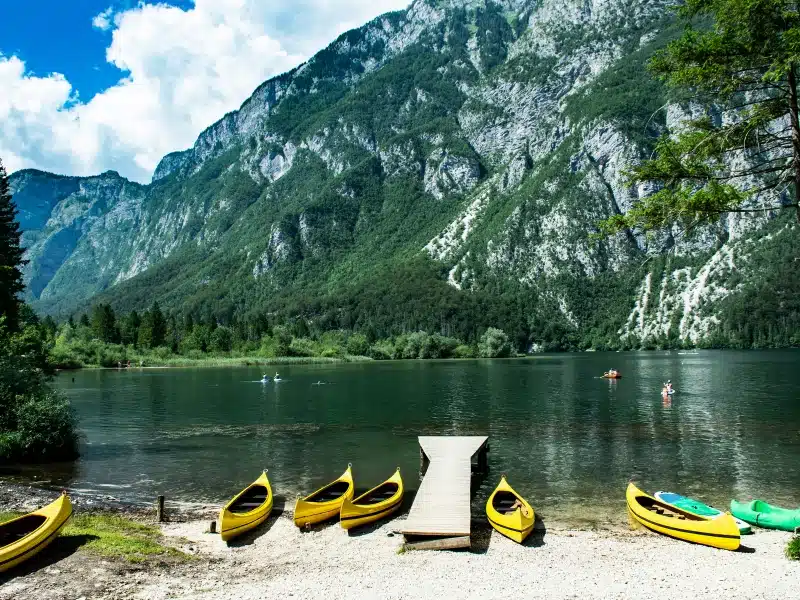 Lake with steep mountain walls and canoes perched in a pebbly beach