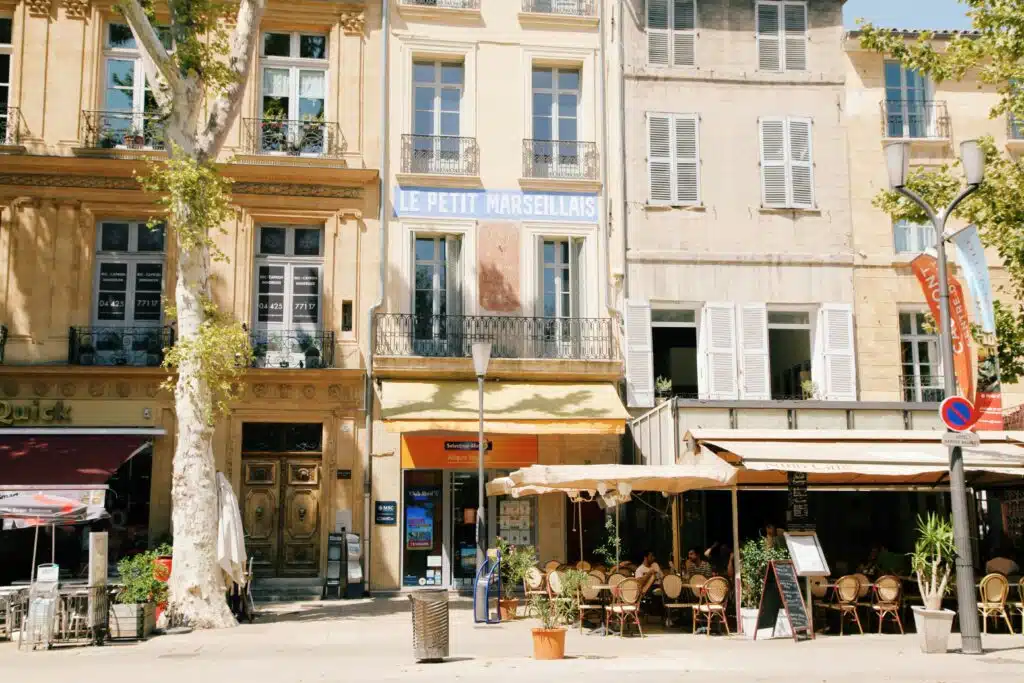 Restaurants and bars line a city street in provence with Sycamore trees providing shade