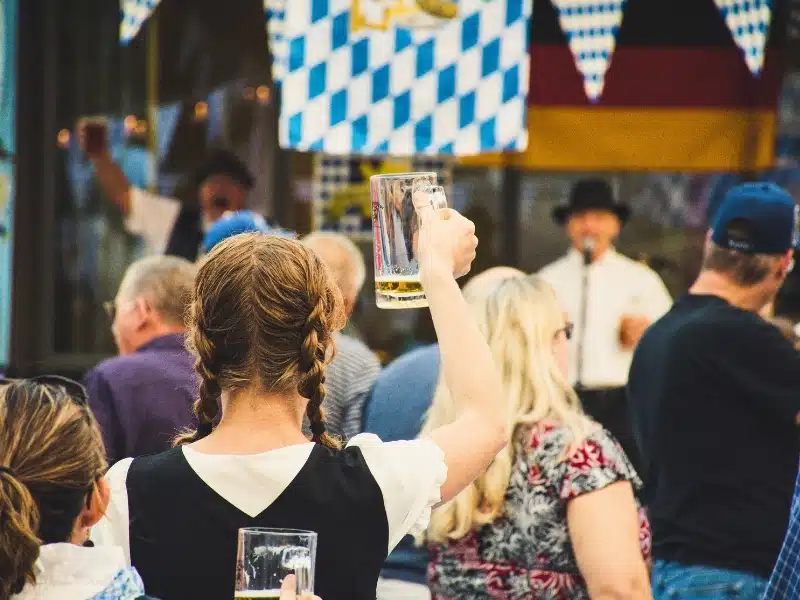Woman with plaits holding a beerstien up to singers in a crowd of people