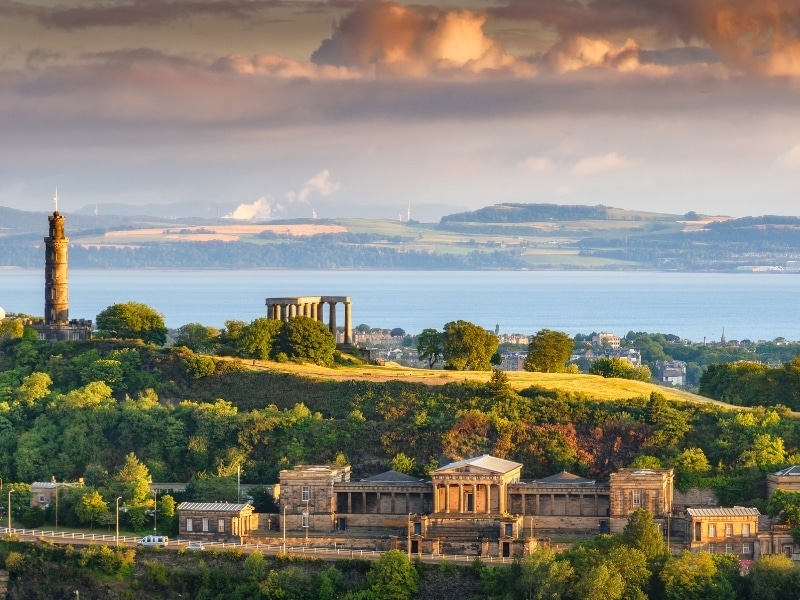 View across a hillside of National Monuments in Edinburgh across to the Firth of Forth