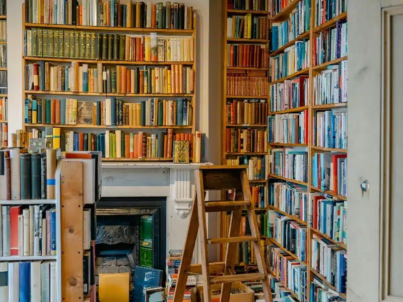 Fully laden bookshelves around. acast iron Victorian fireplace with a step ladder available