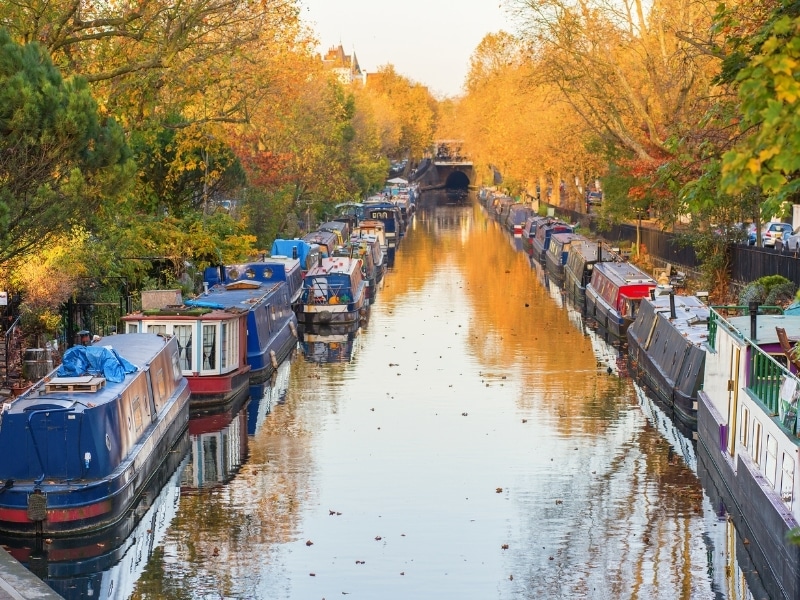 Autumn colors reflecting in a canal lined with canal boats 
