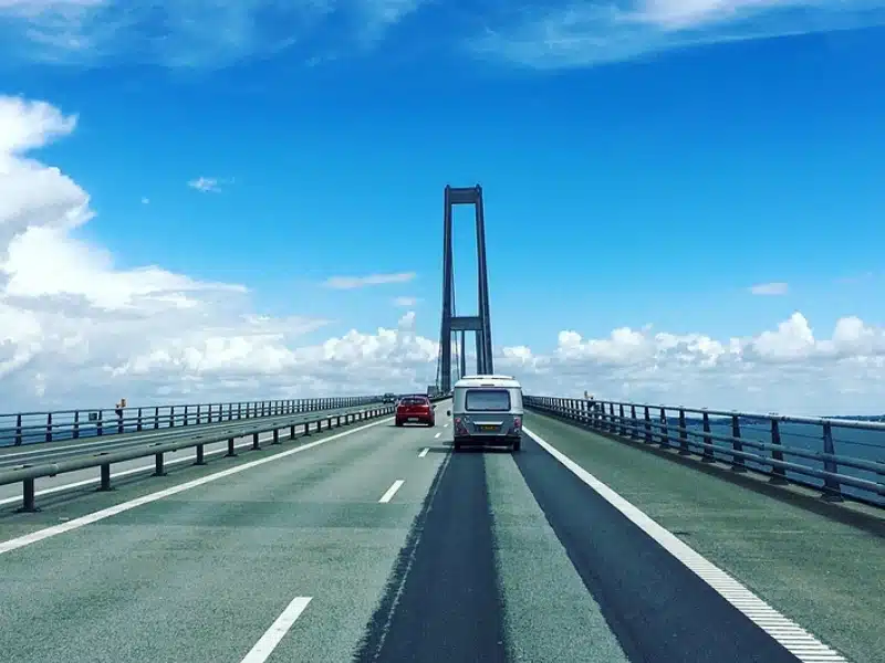 silver caravan on a large bridge with blue sky