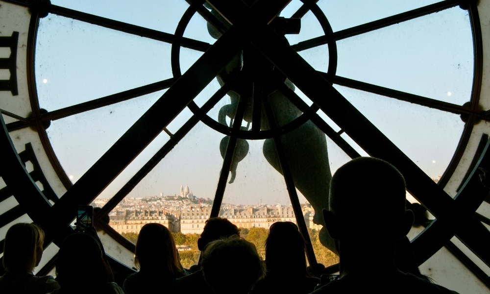 People in front of a large clock looking through to a distant view
