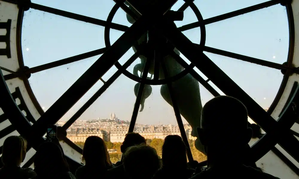 People in front of a large clock looking through to a distant view