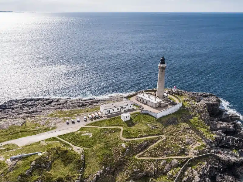 Lighthouse with white buildings on a cliff above the sea