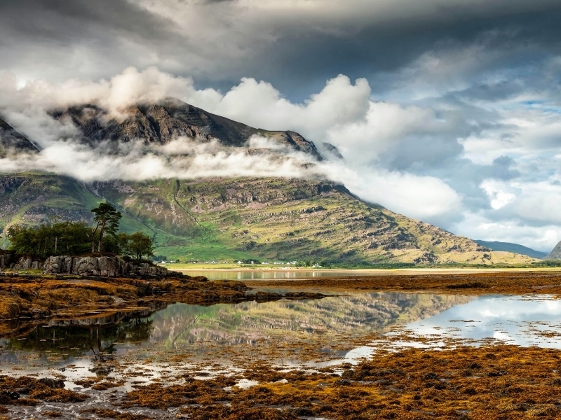 Loch with a small shore village in the distance backed by large craggy mountains