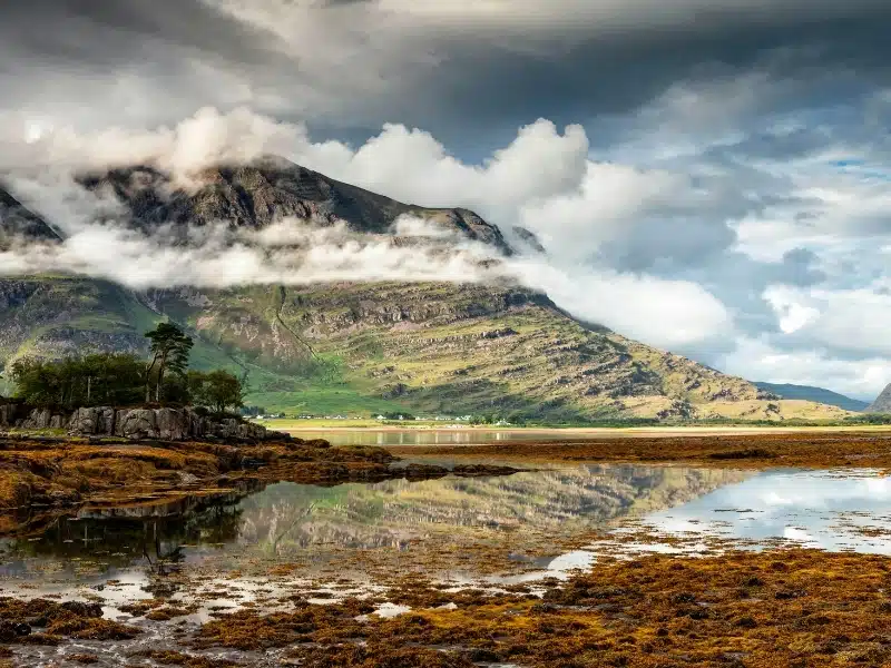 Loch with a small shore village in the distance backed by large craggy mountains