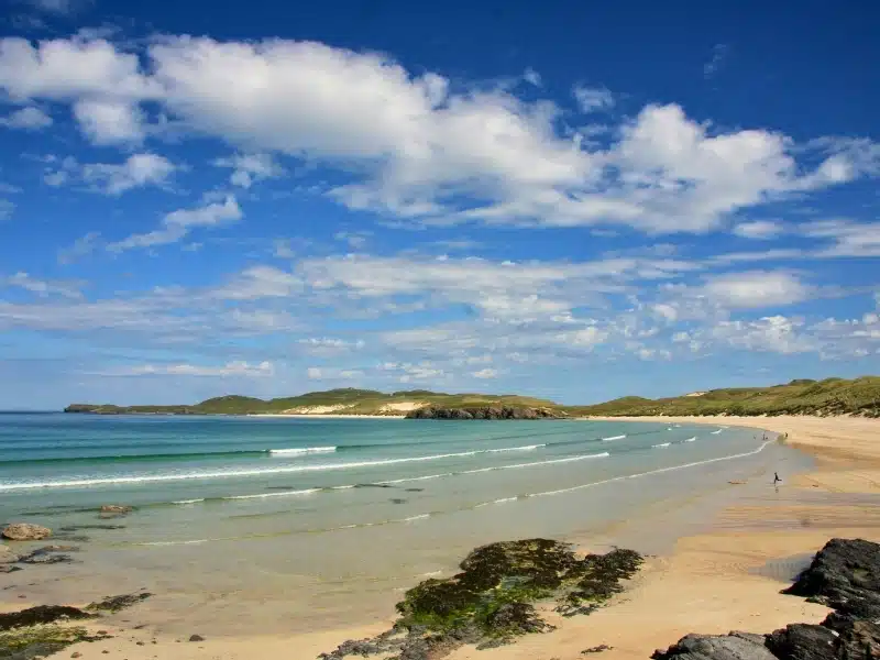 Vast crescent beach of white sands and gently lapping turquoise waters backed by grassy dunes