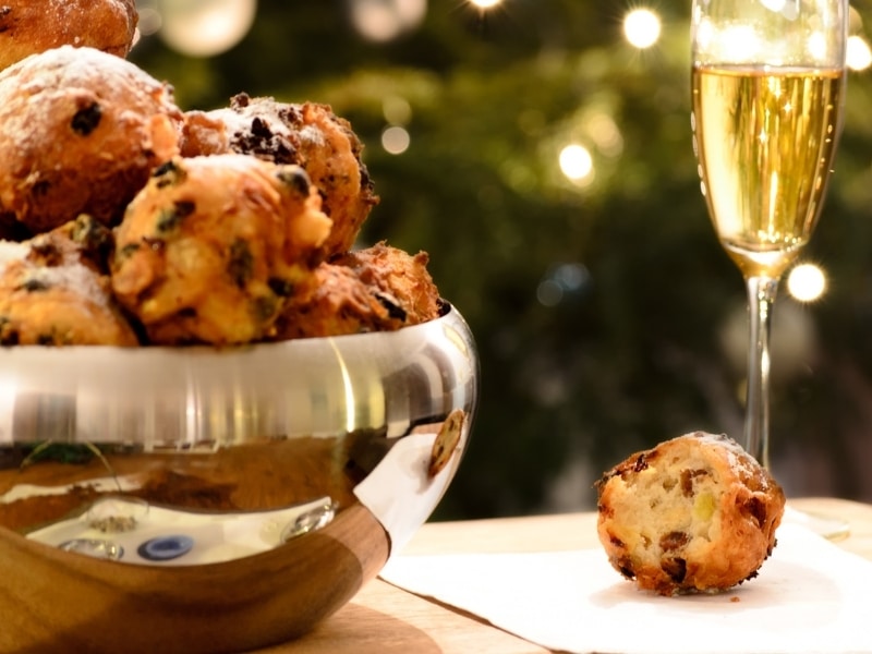 Bowl of fired dough balls filled with raisins and a glass of champagne