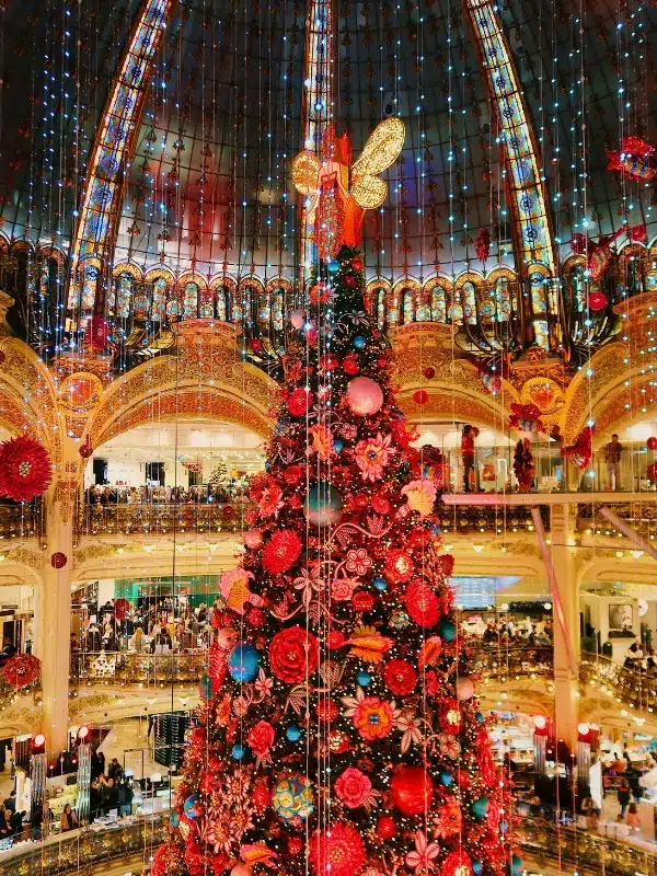 Red and gold fantastical Christmas tree surrounded by fairy lights at Galeries Lafayette in Paris, France