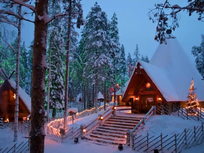 A frame log cabins in. asnowy wood with a lit up Christmas tree