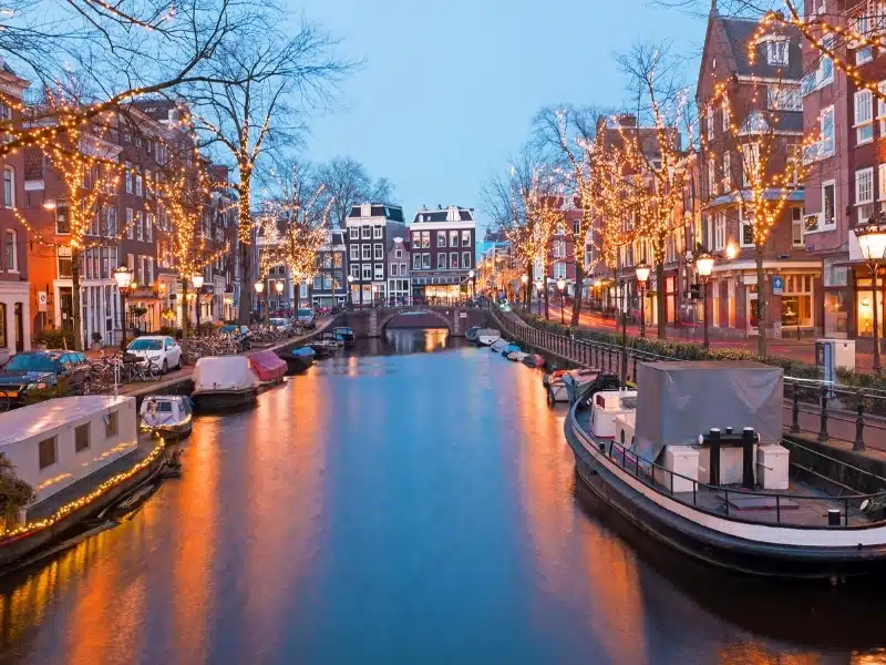 Canal lined with boats and trees with twinkling fairy lights