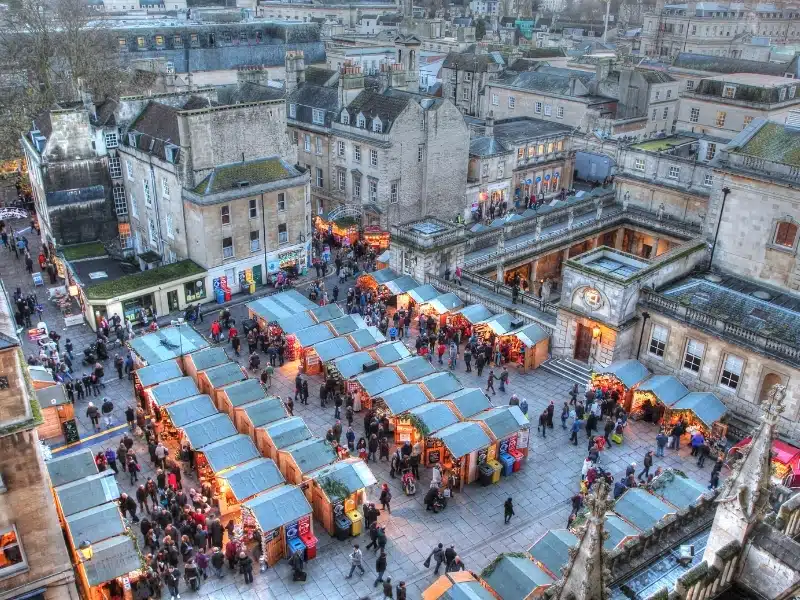 Small wooden huts of a Christmas market surrouned by historic stone buildings
