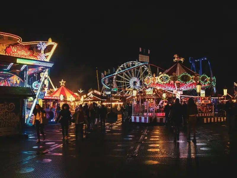 Fairground lit up at night with a ferris wheel and rollercoaster