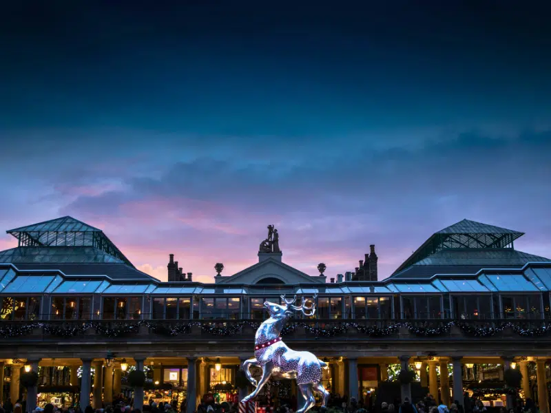 Large silver reinde statue mounted in front of a building with glass roof and stone pillars