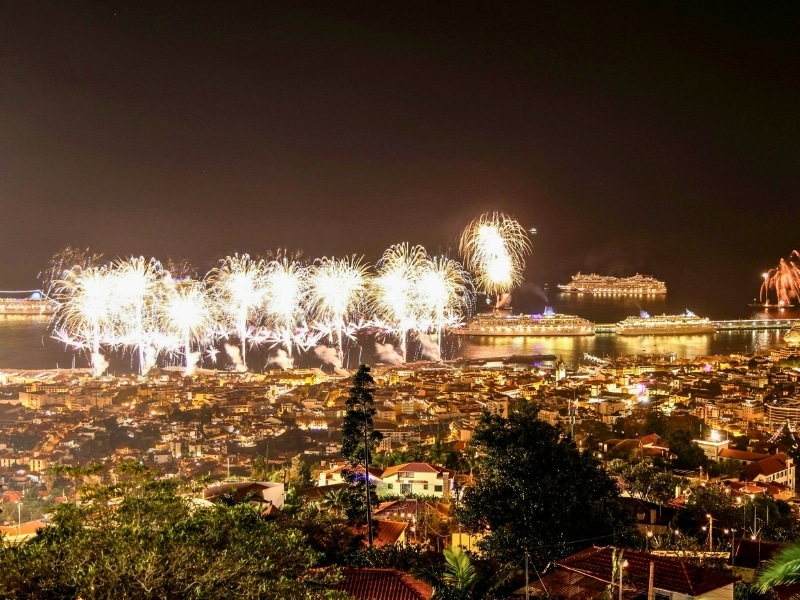 Christmas firework display over a city with cruise ships lit up in the nearby ocean