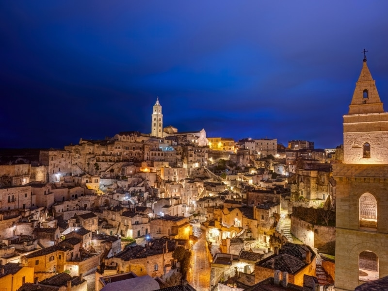 Town of cave houses and stone churches lit at night