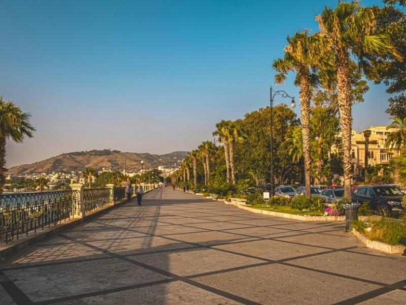 Elegant seaside promenade lined with palm trees and wrought iron railings