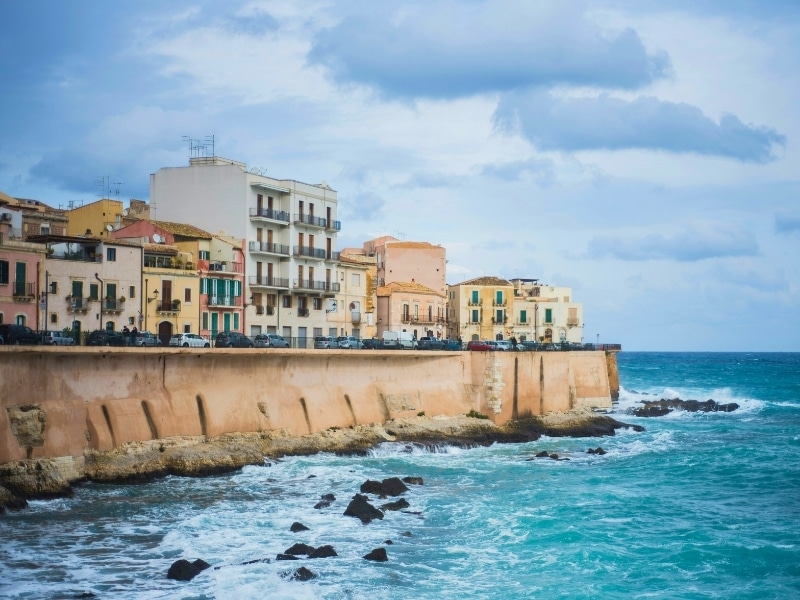 Pastel painted houses above a defensive sea wall on a rough winter's day
