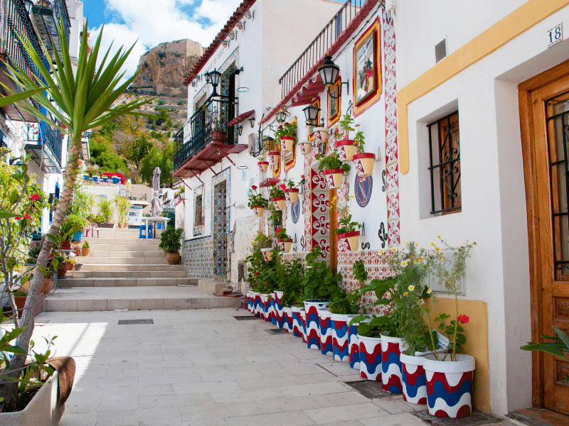 a Spanish street lined with colorful tiled houses and flowers
