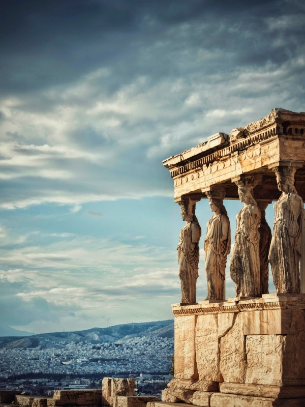 View over a city of white buildings with a Roman temple in the foreground