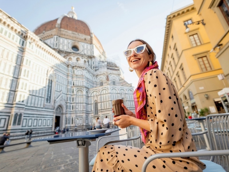 Woman in Florence Italy wearing a camel colored spotted dress and drinking coffee
