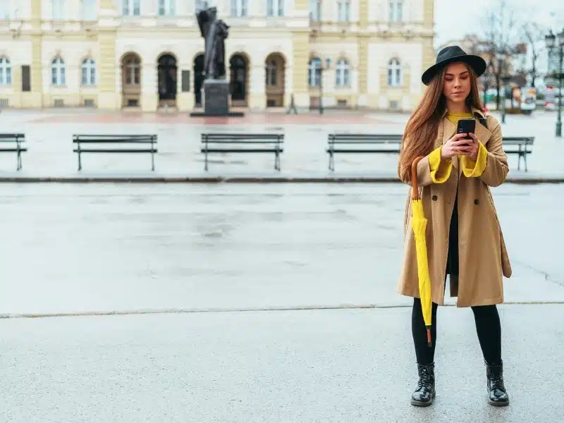Woman in Wroclaw Poland wearing a raincoat and carrying an umbrella whilst taking a selfie
