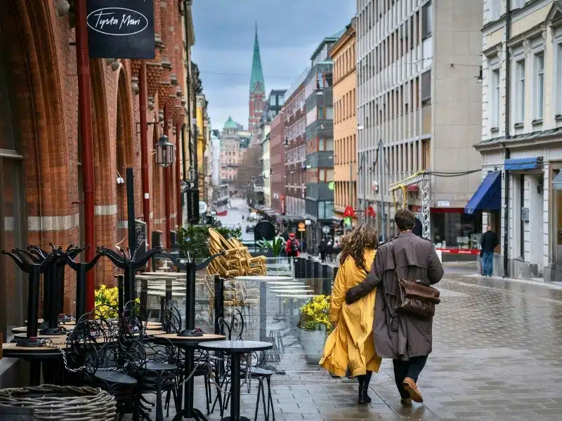Couple in raincoats walking down a wet street in Stockholm Sweden
