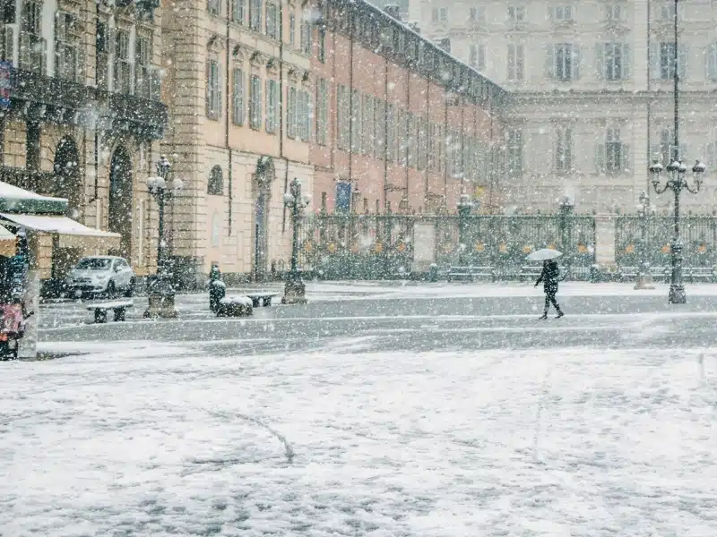 Turin italy in winter, tourist in the main square under the snow with an umberella