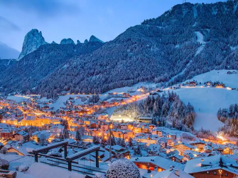 Villige lit at night surrounded by snowy mountains