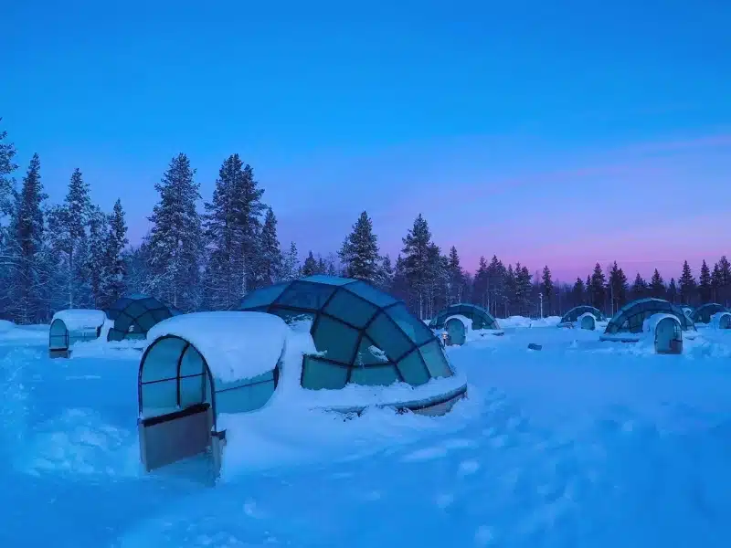 Beautiful shot of pristine snow slightly covering the cool glassy igloos serving as tourist observatories. 