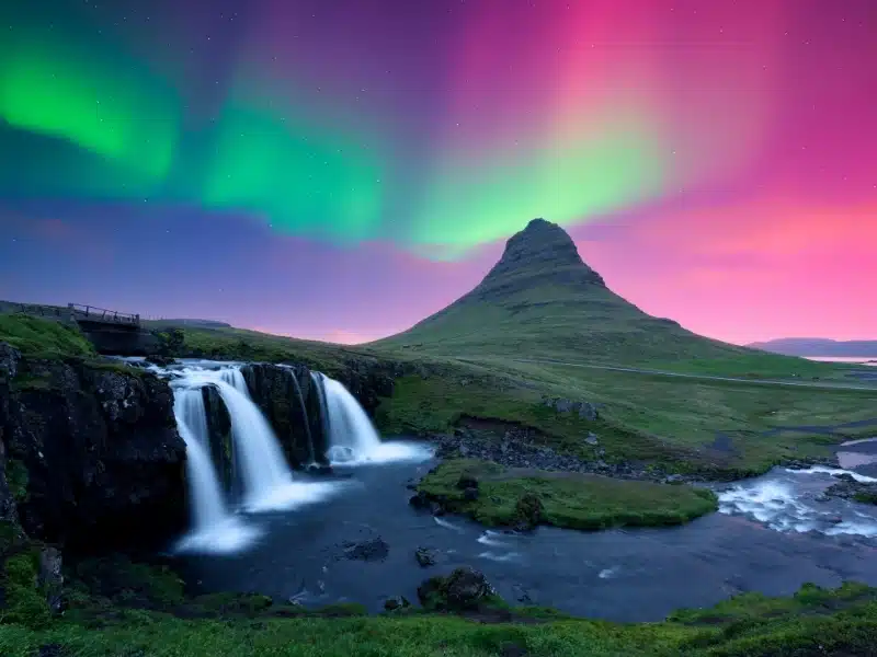 Incredible icelandic landscape with Kirkjufellsfoss waterfall under incredible sky with Northern lights. 