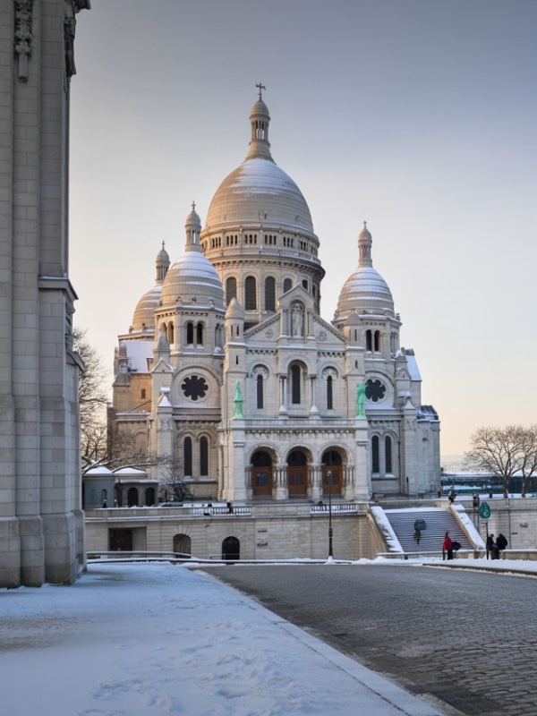 Sacre Coeur Basilica in Montmartre, Paris, framed by a light dusting of fresh snow.