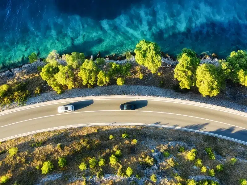 View of the road along the coast from the drone. Travel by car in summer time. The sea coast and the road. The coast of Europe.